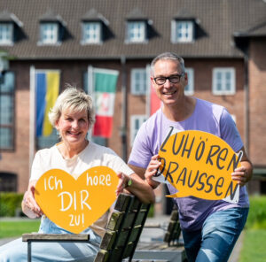 Angelika Kelch-Winter, von links, und Klaus Winter werben für ihr Projekt am Freitag, den 19. Juli 2024, auf einer Bank in Dinslaken vorm Rathaus im Stadtpark. Klaus Winter möchte ehrenamtlich das Projekt zuhören draussen in Dinslaken aufbauen und sucht Mitstreiter. Foto: Volker Herold / FUNKE Foto Services